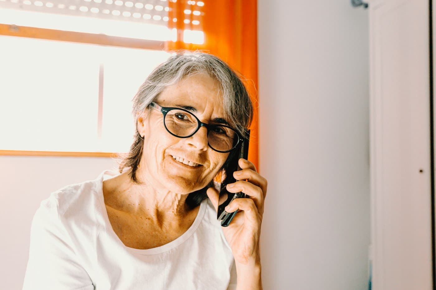 Žena s brýlemi telefonuje a usmívá se